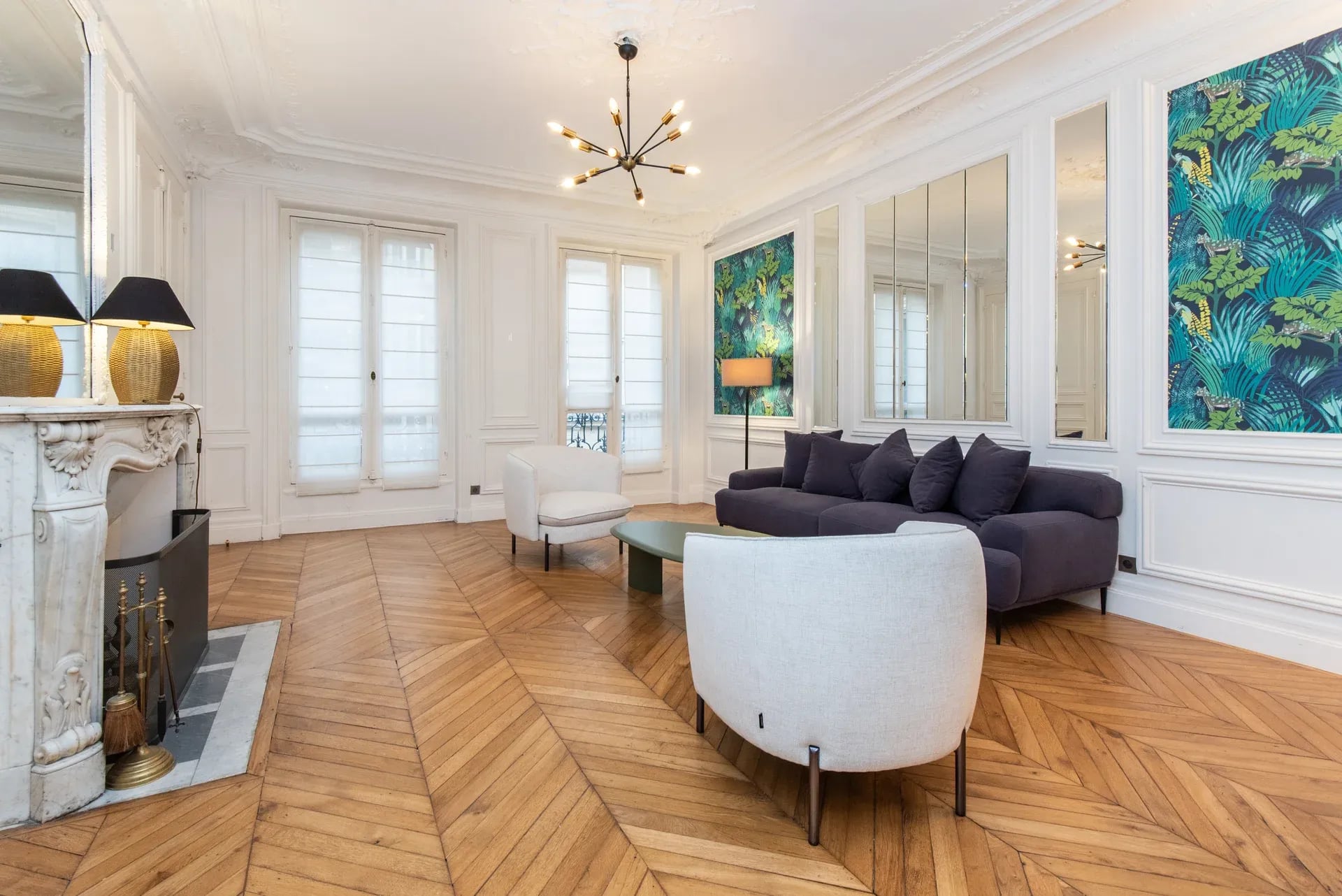 Salon haut de gamme baigné de lumière naturelle, parquet chevron, cheminée sculptée, baies vitrées et mobilier contemporain d'exception.