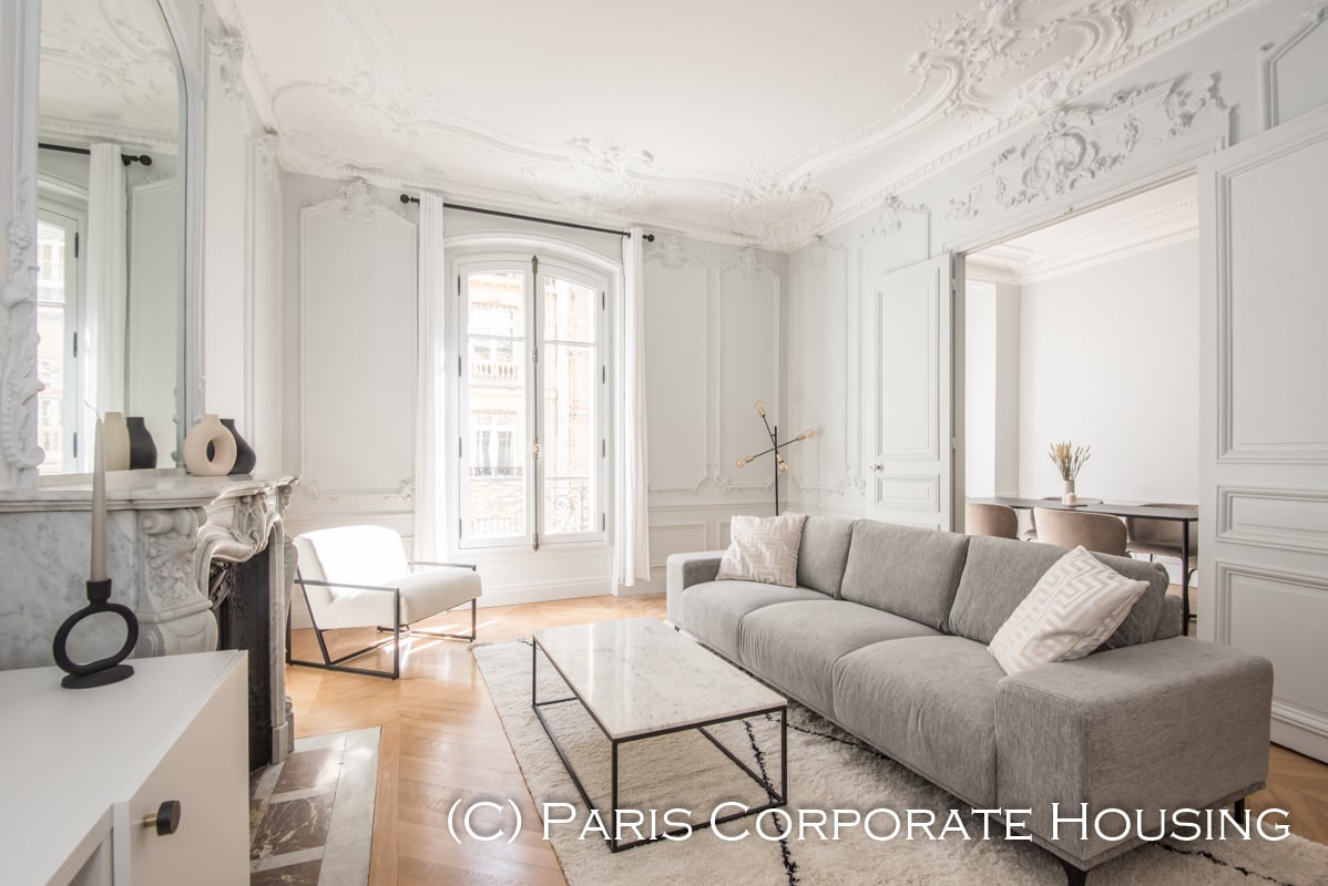 Appartement Haussmannien élégant aux plafonds ornementés, luminosité exceptionnelle, cheminée en marbre et mobilier contemporain raffiné dans quartier prestigieux parisien.