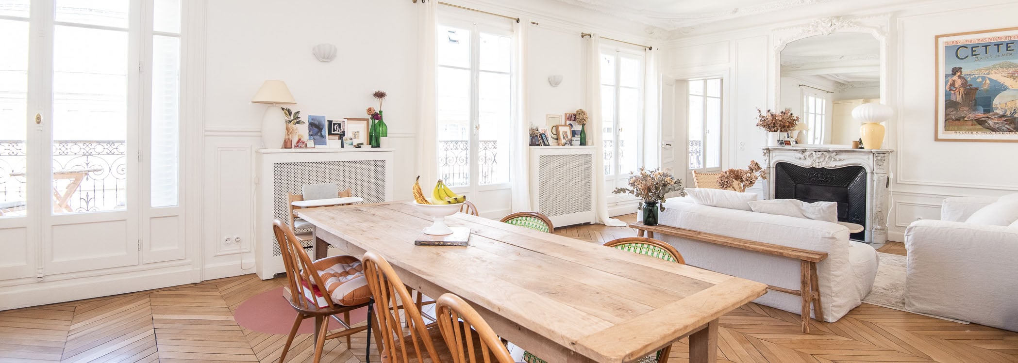 Luminous Haussmann apartment with soaring ceilings, herringbone parquet, and elegant architectural details. Open-plan living seamlessly blends dining and bedroom spaces with abundant natural light.