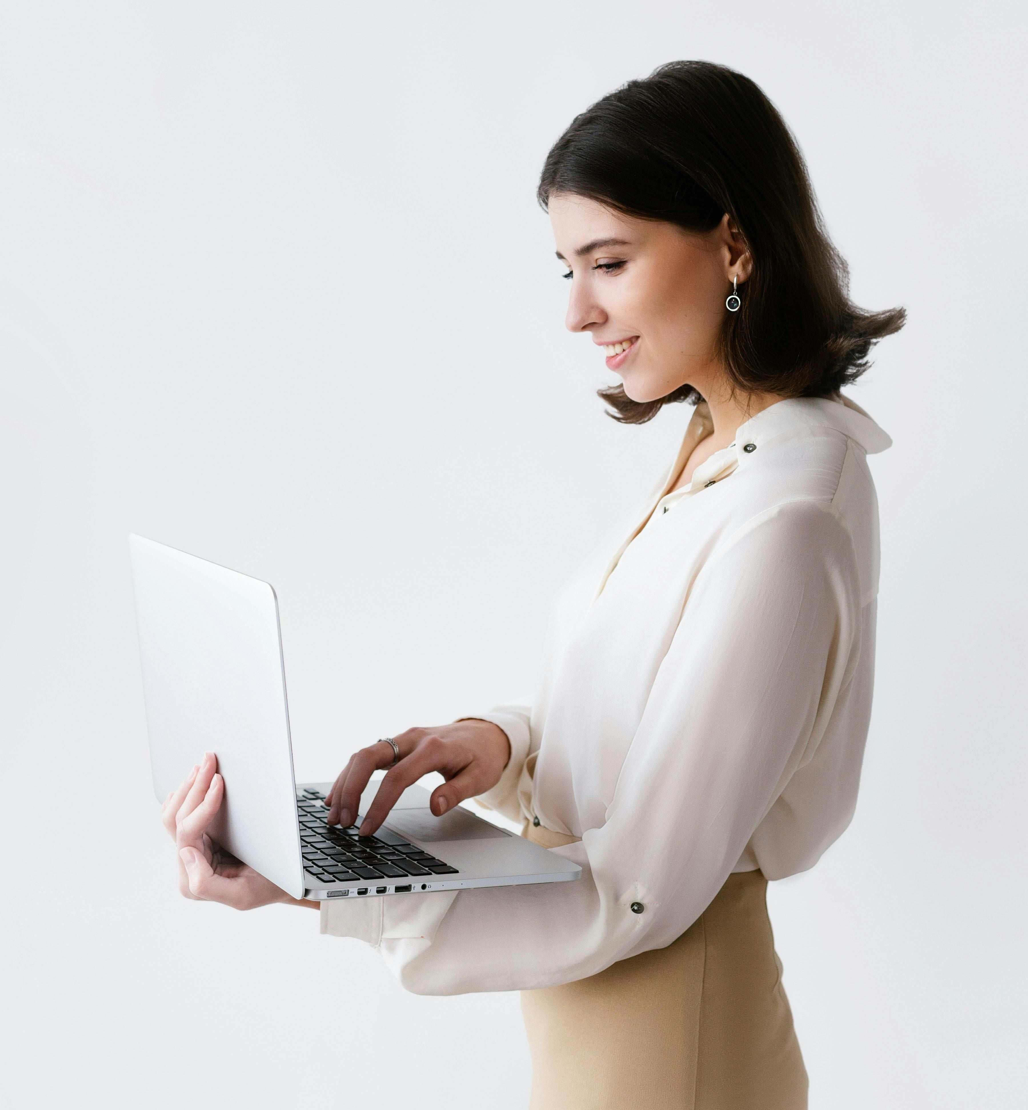 Femme professionnelle travaillant sur ordinateur portable dans un espace lumineux et épuré. Environnement moderne aux lignes épurées, lumière naturelle généreuse et design contemporain haut de gamme.